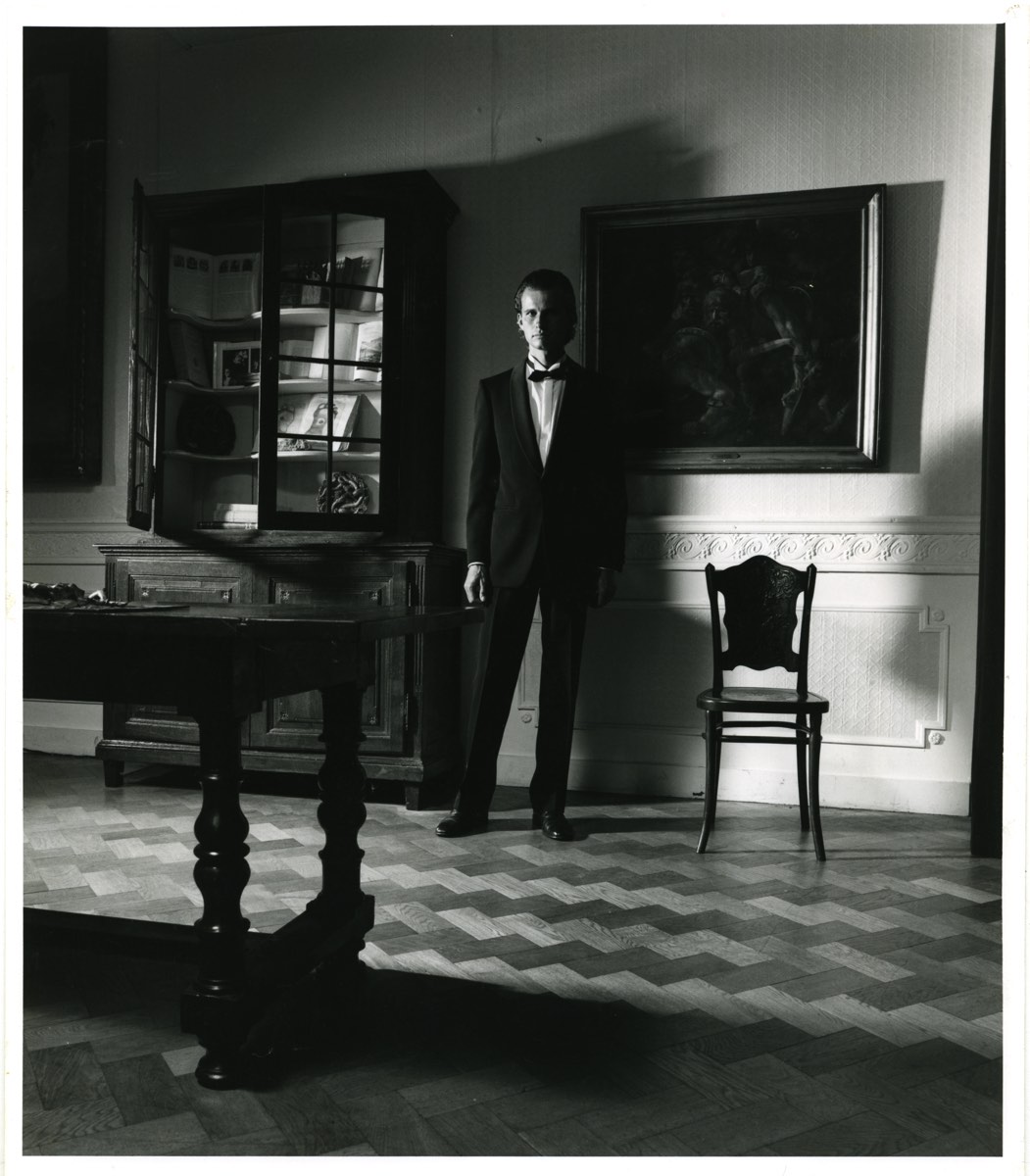 Chambre d'ennemi, 1986 : le garçon d'intérieur en smoking, debout près de la vitrine et du tableau.